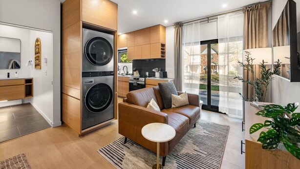 Un appartamento moderno con cucina, zona giorno con divano e lavatrice e asciugatrice integrate.