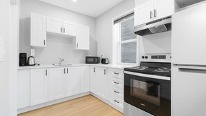 Cocina moderna con armarios blancos, estufa de acero inoxidable y microondas.