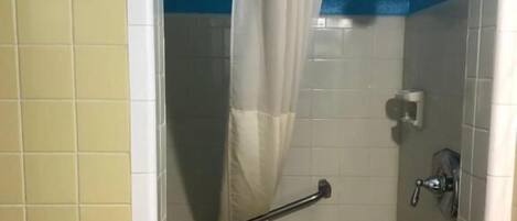 A small, enclosed shower area with a towel rack, a shower curtain, and a handheld showerhead.