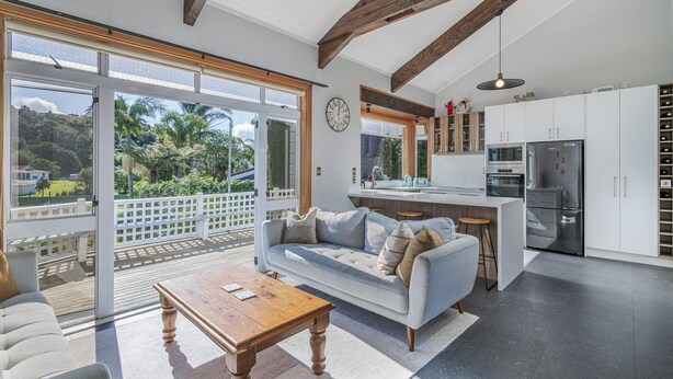 A modern kitchen with white cabinets, a stainless steel refrigerator, and a wooden dining table.