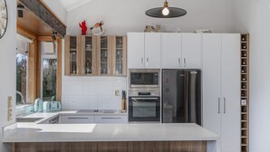 A modern kitchen with a central island, white cabinetry, and a built-in wine rack.