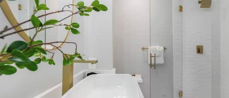 A modern bathroom with a freestanding bathtub, a glass shower enclosure, and a minimalist design.
