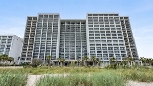 Un hotel di grattacielo con numerosi piani, una facciata uniforme e vista sulla spiaggia.