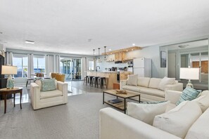 A spacious living area with a sofa, coffee table, and a kitchen in the background.