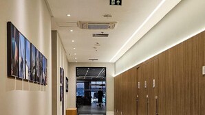 A hallway with a long wooden table, lockers, and a door leading to a room with a view. - Suite Luxo a 5min do aerop de Congonhas (São Paulo)