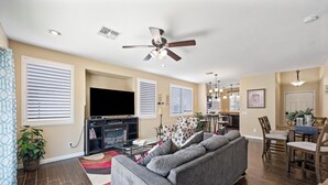 A living room with a gray sofa, a flat-screen TV, and a ceiling fan. - Stay with the Shay’s (Phoenix)
