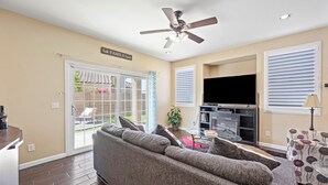 A living room with a sofa, a TV, and a ceiling fan. - Stay with the Shay’s (Phoenix)