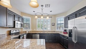 A modern kitchen with granite countertops, stainless steel appliances, and dark cabinetry. - Stay with the Shay’s (Phoenix)