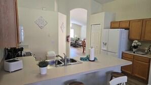 Una cucina moderna con isola centrale, elettrodomestici in acciaio inossidabile, pensili in legno e un'area pranzo sullo sfondo.