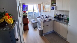 Een kleine keuken met een eethoek, een zithoekje en een aan de muur bevestigde televisie.