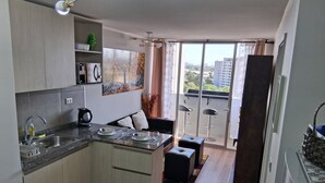 Een moderne keuken met een eethoek, een zithoekje en een stadszicht door grote ramen.