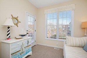 A room with a nautical-themed dresser, a window with blinds, and a bed with a striped pillow. - A Bit O Heaven - 1 Minute to the beach on private road (Oak Island)