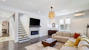 Un salon moderne avec une cheminée, un canapé, une table basse et un escalier.