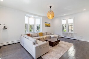 Ein modernes Wohnzimmer mit einer Eckcouch, einem Couchtisch und einer Pendelleuchte.