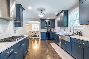 A modern kitchen with dark blue cabinets, a white marble countertop, and a stainless steel range hood. - Boston 5BR Retreat Sleeps 12 Free Parking Backyard (Boston)