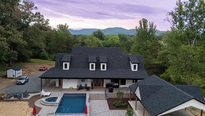A two-story house with a swimming pool, covered patio, and a view of mountains. - New! Secluded Farmhouse Pool + Firepit 14ppl (Faber)