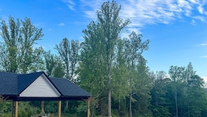 A swimming pool with a covered area and trees in the background. - New! Secluded Farmhouse Pool + Firepit 14ppl (Faber)