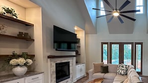 A spacious living room with a fireplace, a large sofa, and a ceiling fan. - New! Secluded Farmhouse Pool + Firepit 14ppl (Faber)