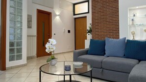A modern living room with a grey sofa, a glass coffee table, and a blue rug. - La Dimora Holiday House (Salerno)