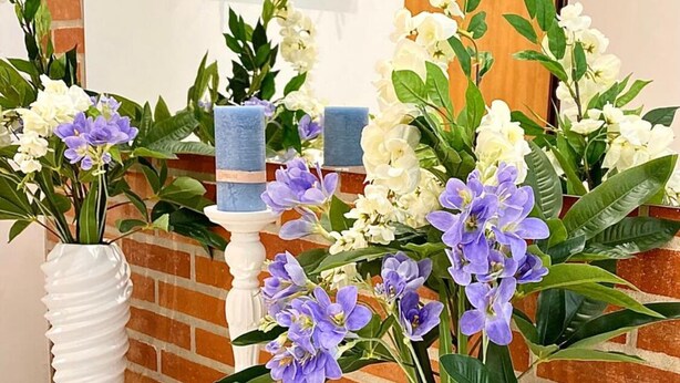 A reception area with a white counter, two white vases with flowers, a candle holder, and a small metal bowl. - La Dimora Holiday House (Salerno)