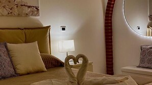 A hotel room with a bed, a heart-shaped towel arrangement, a round mirror, and a wall-mounted artwork. - La Dimora Holiday House (Salerno)