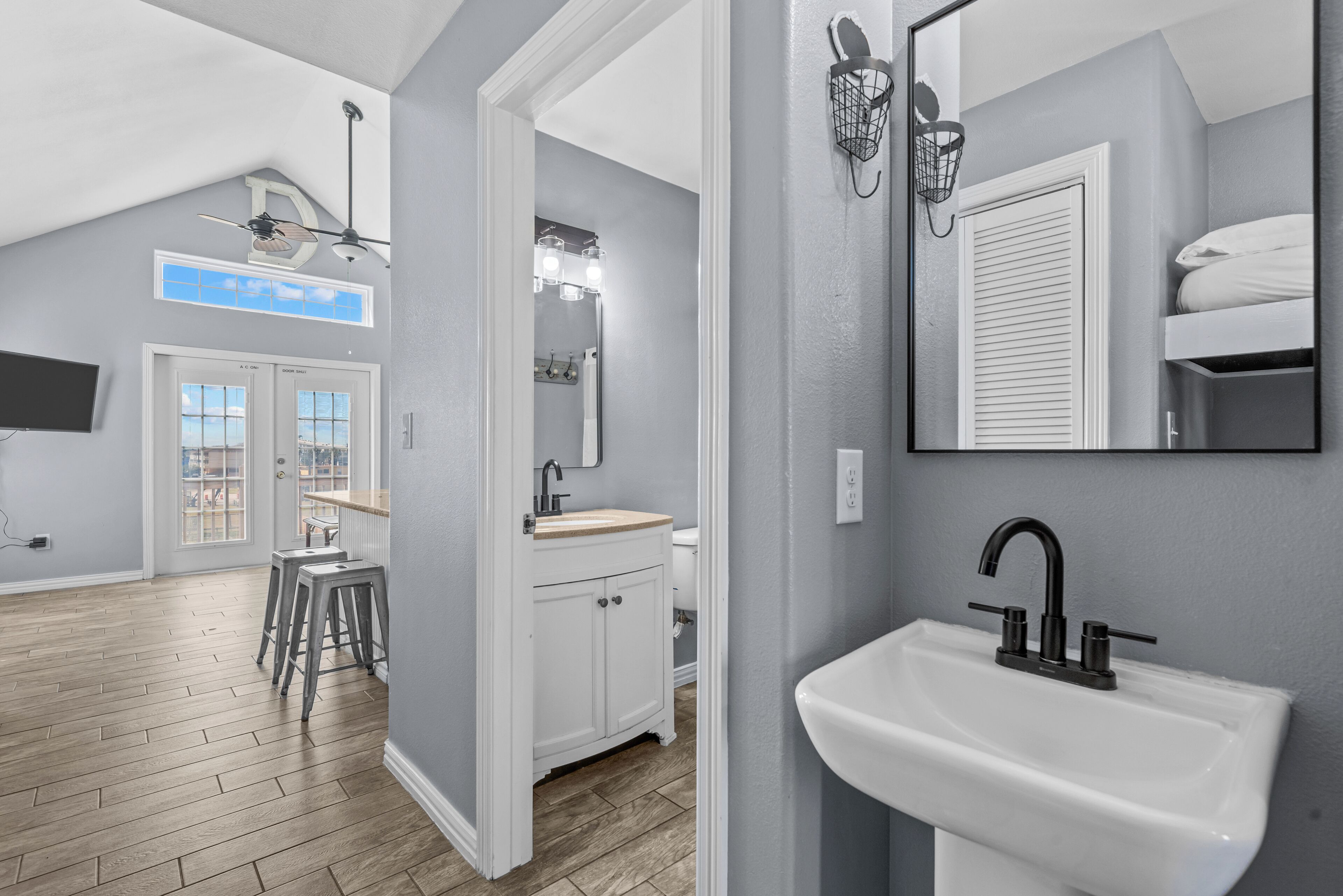 A modern bathroom with a white sink, a mirror, and a ceiling fan.