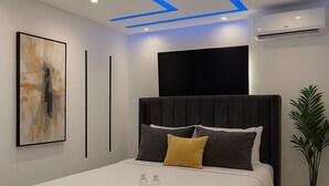 Un dormitorio moderno con una cama grande, un televisor de pantalla plana y una planta en maceta.