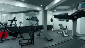 Un gimnasio moderno con equipamiento cardiovascular, máquinas de pesas y una banca.