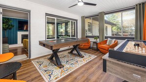 Una sala de estar moderna con mesa de ping pong, mesa de fútbol de mesa y una zona de estar con sillones naranjas.