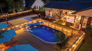 Una piscina con tobogán, terraza y un mural en la pared de al lado.