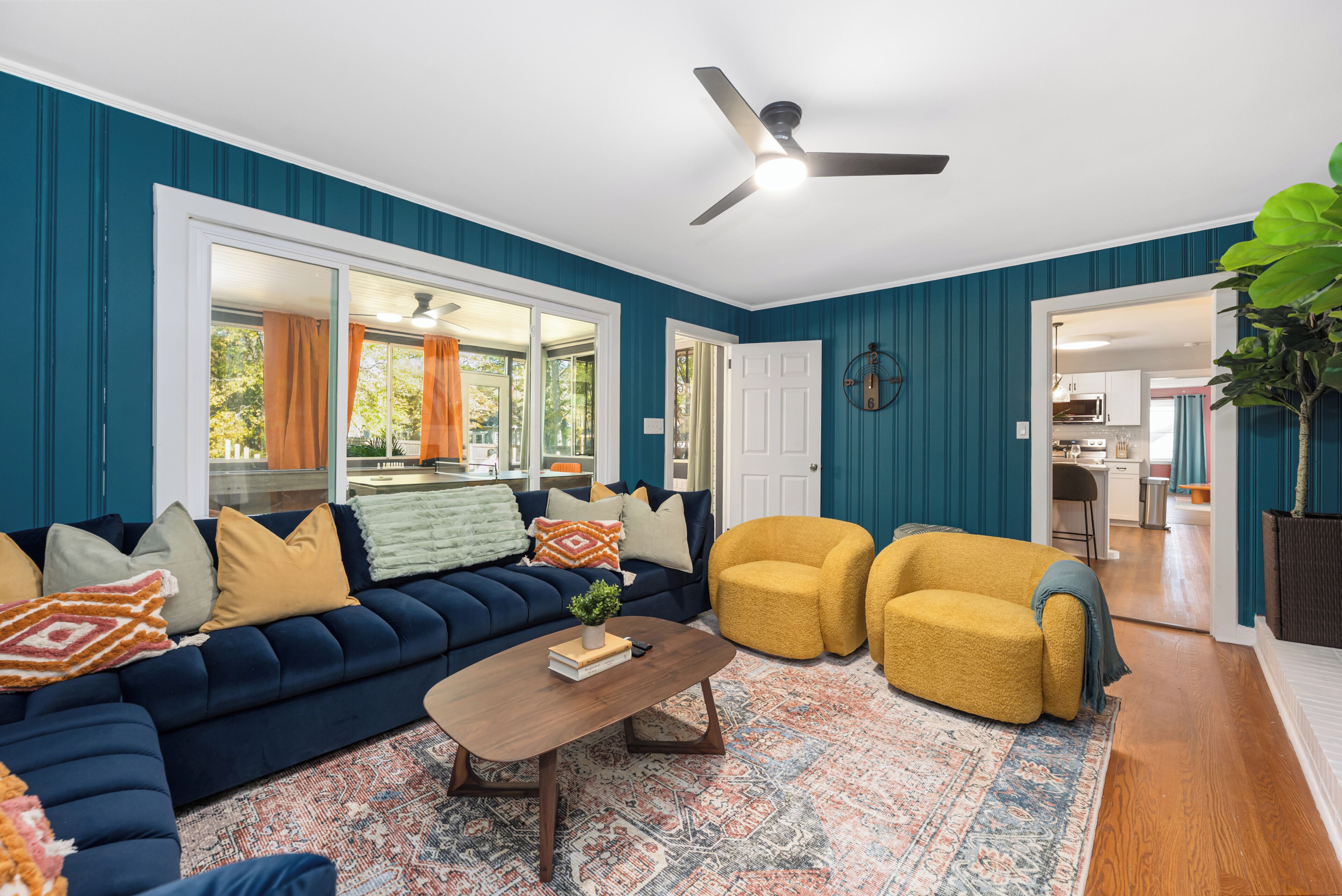 A living room with a dark blue sofa, yellow armchairs, a coffee table, and a patterned rug.
