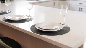 Una cocina moderna con una isla central, luces colgantes y armarios blancos.