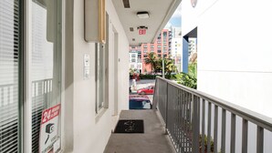 A narrow corridor with a metal railing, a doormat, and a sign indicating 24-hour surveillance. - Central Spot+Free Parking+ Steps to DT & Nightlife (Miami)