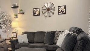 A modern living room with a sectional sofa, a matching ottoman, and decorative wall art. - The Gilliam House (london)