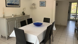 En matplats med ett vitt bord, svarta stolar, en blå skål och en dekorativ hänglampa.