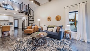 A spacious living area with a blue sofa, a wooden coffee table, and a staircase leading to an upper level.