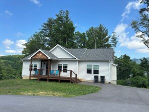 A two-story house with a porch, a small deck, and a driveway leading to the front door. - 3-bedroom house with hot tub 🛀 in peaceful Fairview neighborhood (Fairview)