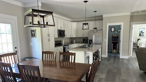 A modern kitchen with white cabinetry, a central island, and pendant lighting.