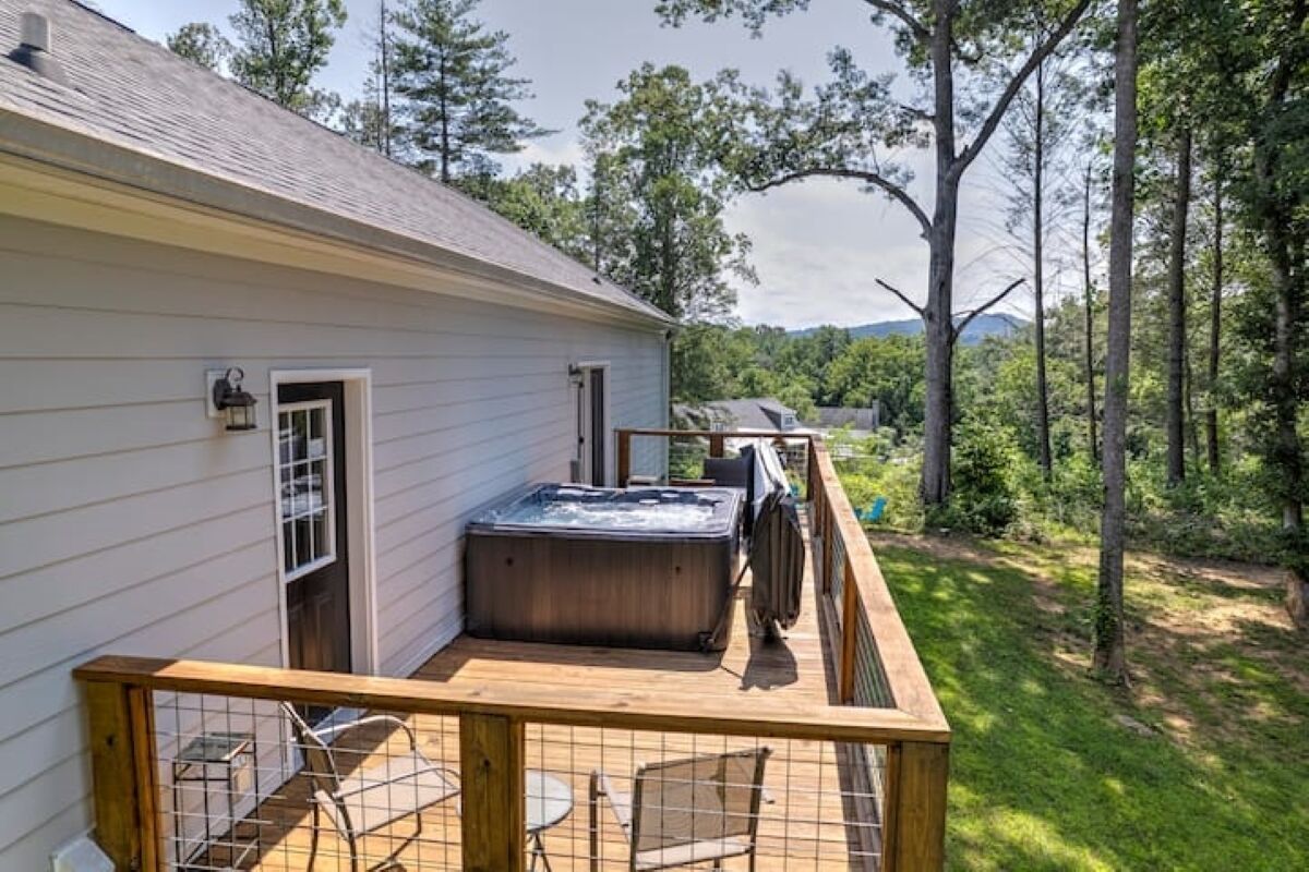 Une maison avec une terrasse, un jacuzzi et une vue sur une forêt.