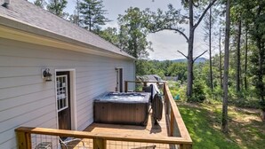 A house with a deck, a hot tub, and a view of a forest.
