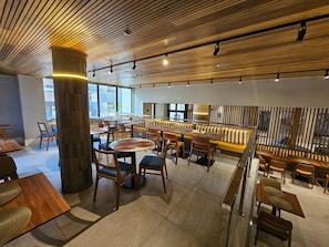 A modern restaurant interior with wooden ceiling, round tables, and cushioned seating. - Luxury suite 5 minutes from Congonhas Airport, queen-size bed + single bed (São Paulo)