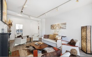 Ein modernes Wohnzimmer mit einer Couch, Sesseln, einem Couchtisch und einer dekorativen Lampe.