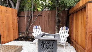 Een terras met twee Adirondack-stoelen, een vierkante tafel en een houten terras.