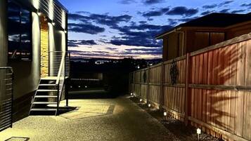 A gravel driveway leading to a building with a staircase and a wooden fence.