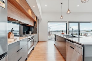 Een moderne keuken met roestvrijstalen apparatuur, houten keukenkastjes en een groot raam met uitzicht op de skyline.