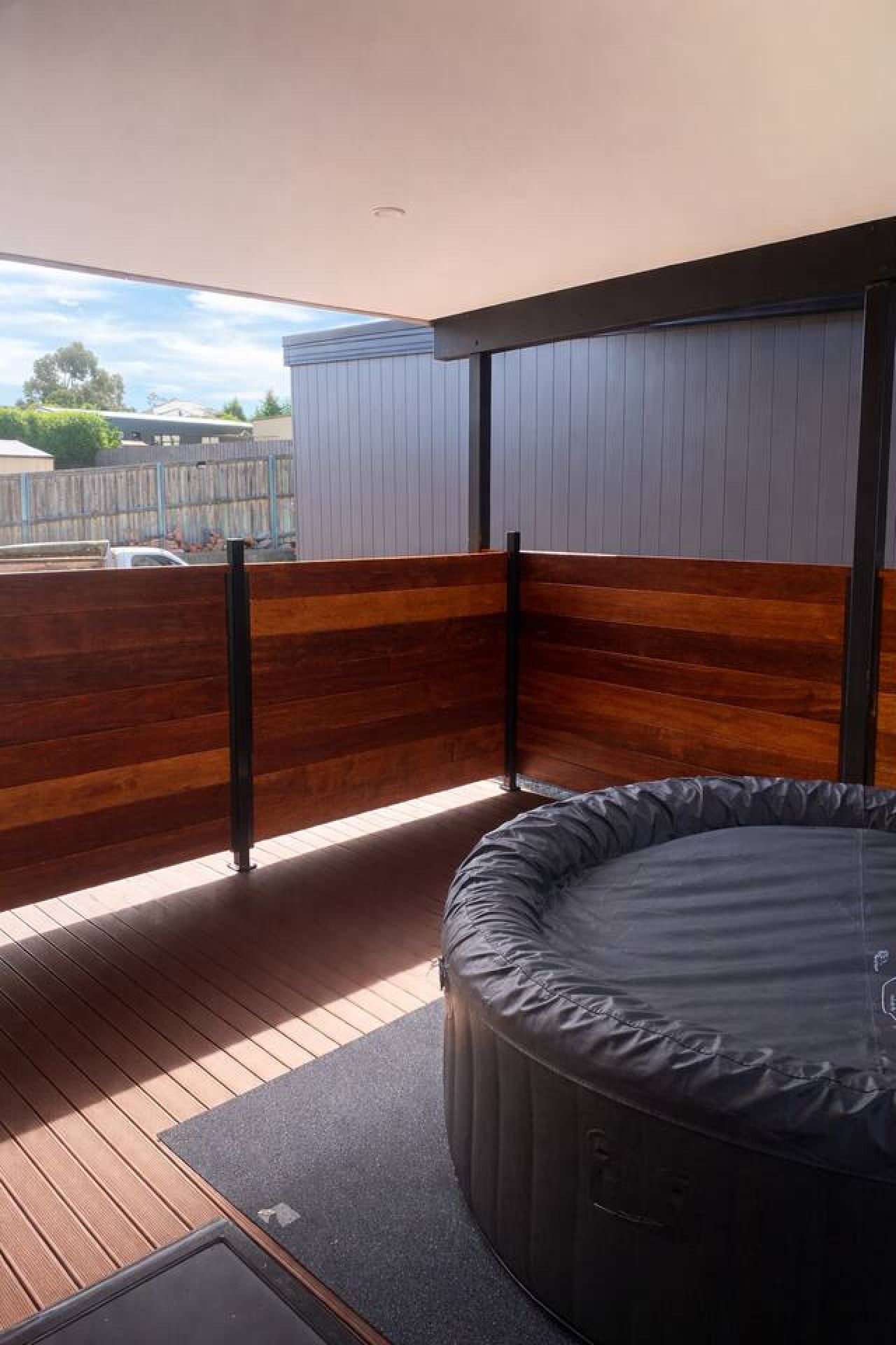 Een hottub op een houten terras, met uitzicht op de lucht en een hek op de achtergrond.