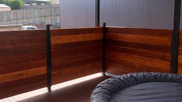 Een hottub op een houten terras, met uitzicht op de lucht en een hek op de achtergrond.