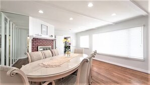 A dining area with a round table, six chairs, a brick fireplace, and a large window with blinds. - 3-bedroom house, pool and other amenities in amazing Tarzana area of Los Angeles (Los Angeles)