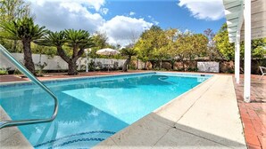 A rectangular swimming pool with a tiled edge, surrounded by a brick patio. - 3-bedroom house, pool and other amenities in amazing Tarzana area of Los Angeles (Los Angeles)