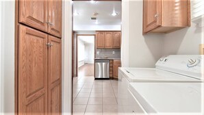 A laundry area with a washing machine and dryer, wooden cabinets, and a stainless steel dishwasher. - 3-bedroom house, pool and other amenities in amazing Tarzana area of Los Angeles (Los Angeles)